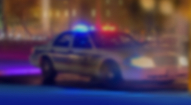 Blurred out photo of a police car with red and blue siren lights on. 