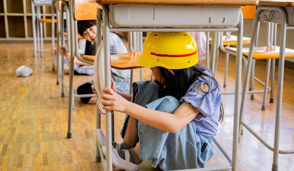 Students sitting underneath school desks