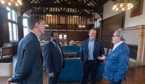Four men in suits speaking to one another in office