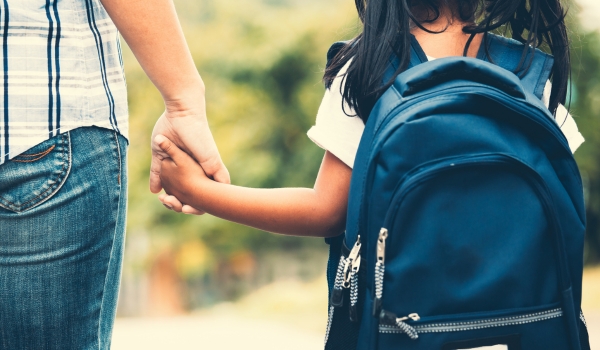 Cute asian pupil girl with backpack holding her mother hand and going to school in vintage color tone