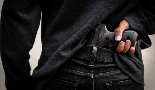Person holding a gun behind their back
