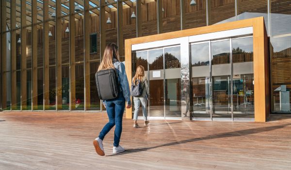 Two college students entering the university to attend classes on a sunny day