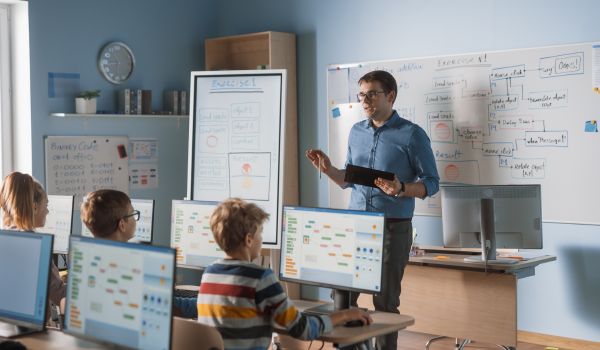 Teacher instructing students in a computer classroom.