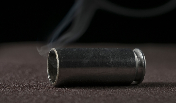 The shotgun cartridge lies on the floor or on the road. There is smoke from the cartridge case, she recently shot