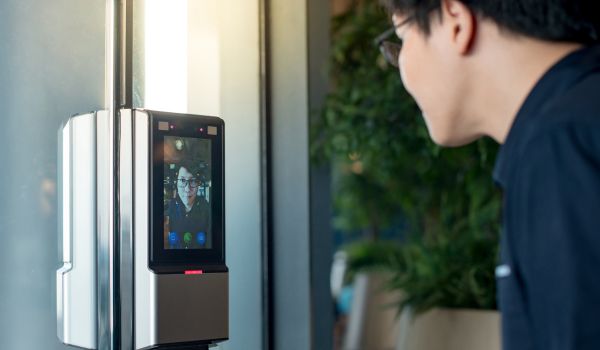 man using face scanner to unlock glass door in office building