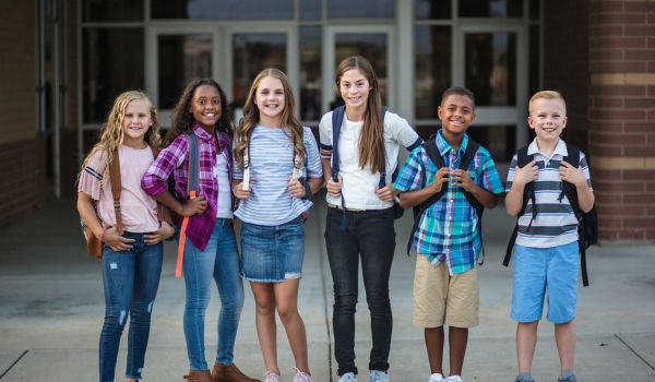 K-12 learners in front of a school.