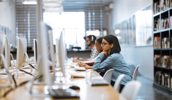 Shot of a group of university students working on computers in the library at campus