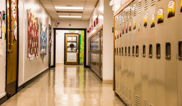 An empty school hallway lined with student lockers on one side and decorated bulletin boards on the other.