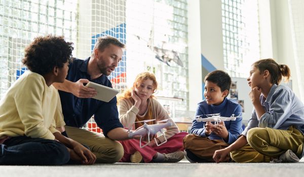 Teacher explaining group of children safety precautions before launching flying drones