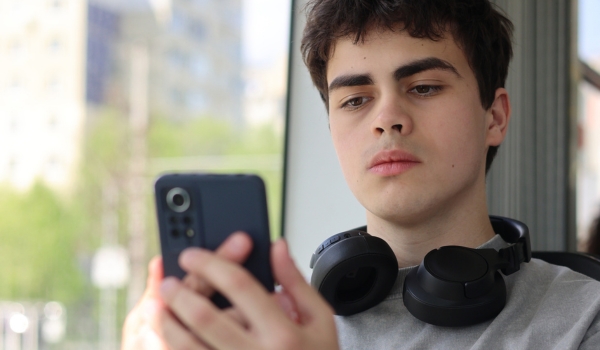 Teenage boy with smartphone looking tired and worried, digital overload and cyberbullying concept