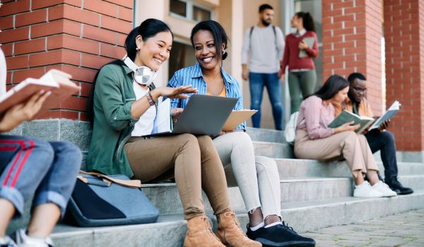 Students using laptop in front of university building