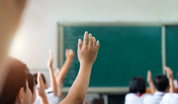 Students raising hands in classroom