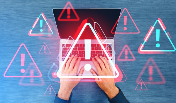 Person using laptop with warning signs displayed, on blue wooden background, concept of cybersecurity