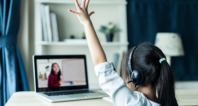 Student raising her hand during remote instruction from teacher. 