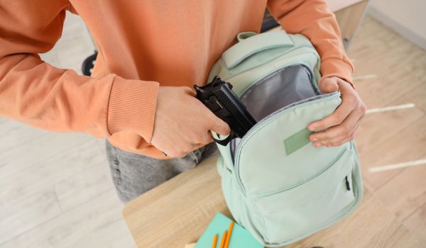 Person putting gun in school bag